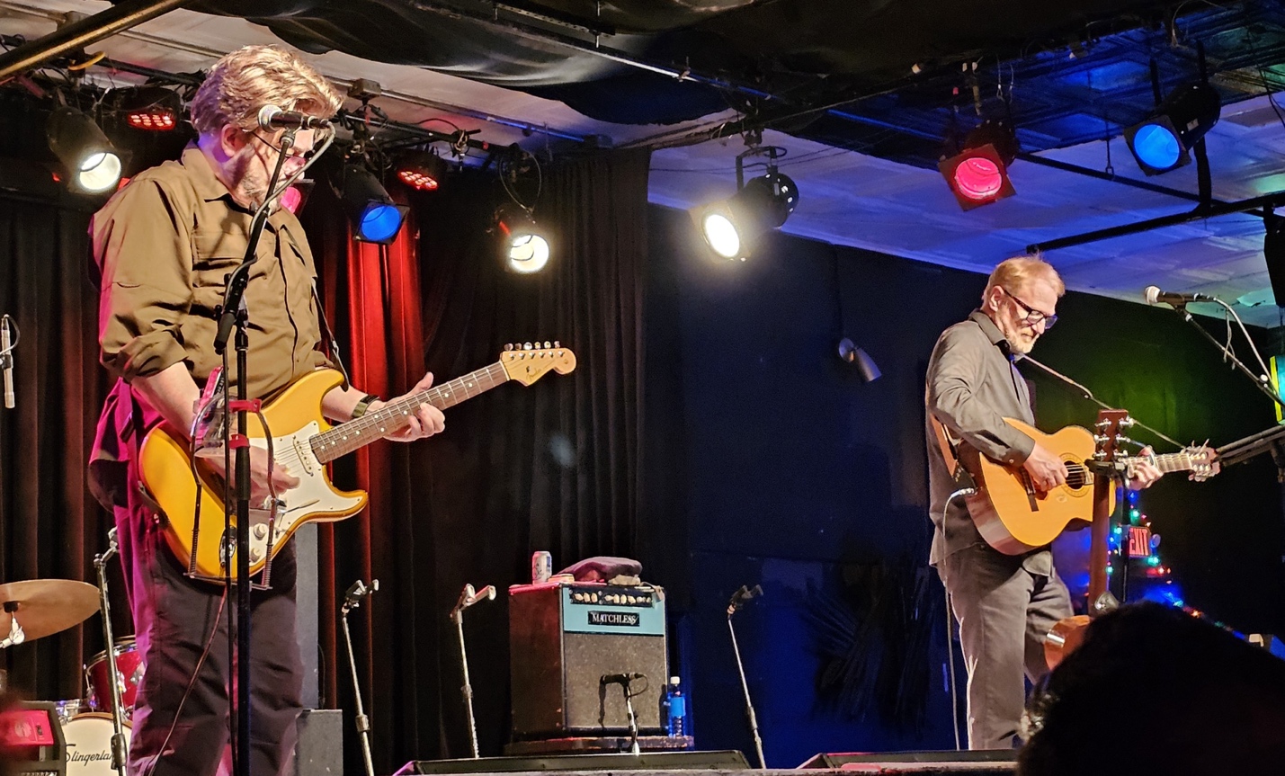 A group of men playing guitars on a stageDescription automatically generated